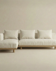 The Islet Modular Sofa | Fabric • M3 by Wooden Stories is a modern, minimalist beige sectional with three seat and back cushions plus a left-side chaise, set against a matching beige background.
