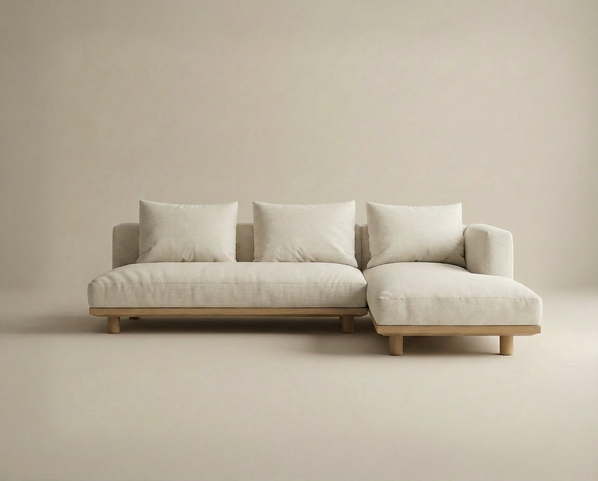 The Islet Modular Sofa | Fabric • M3 by Wooden Stories is a modern beige sectional with three large matching cushions, a right-side chaise lounge, a wooden base, and short wooden legs, displayed against a plain light background.