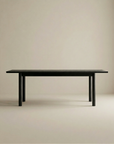 The Wooden Stories Itamae Dining Table in Black Oak features a minimalist, rectangular design with four legs and Scandinavian style, displayed against a light beige background.
