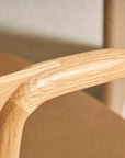 Close-up of the Inlay Dining Chair | Light Oak and Leather by Wooden Stories, highlighting the curved solid oak armrest, leather seat, and natural wood grain. The craftsmanship stands out against a softly blurred background.