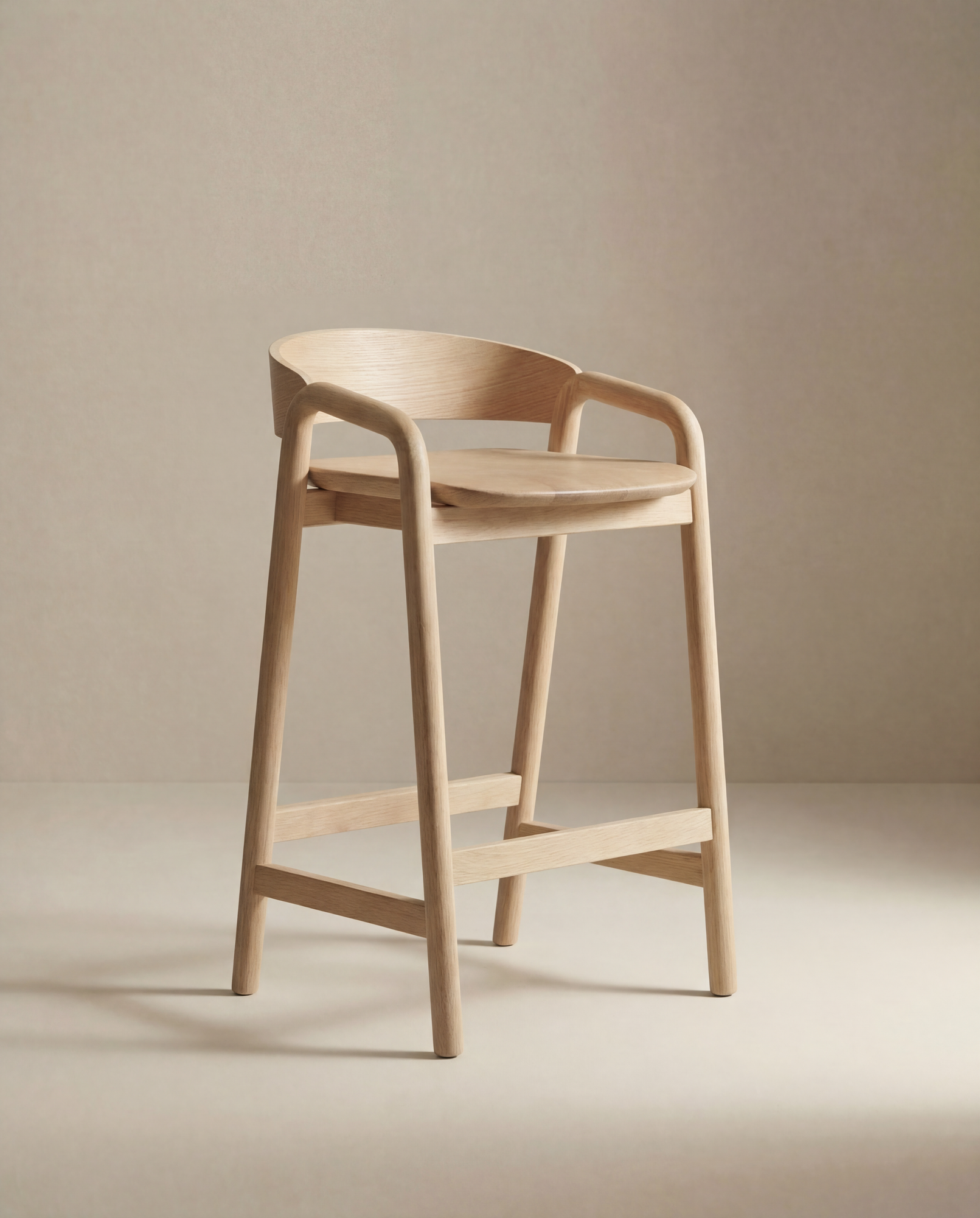 The Inlay Counter Stool | Wood Seat by Wooden Stories features a modern Danish design with a curved backrest, armrests, and footrest in smooth light wood—ideal for stylish kitchen island seating against a neutral beige background.