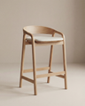 The Inlay Counter Stool | Fabric Seat from Wooden Stories features a modern design with a solid oak frame, curved backrest, and a light fabric-cushioned seat, showcased against a plain beige background.