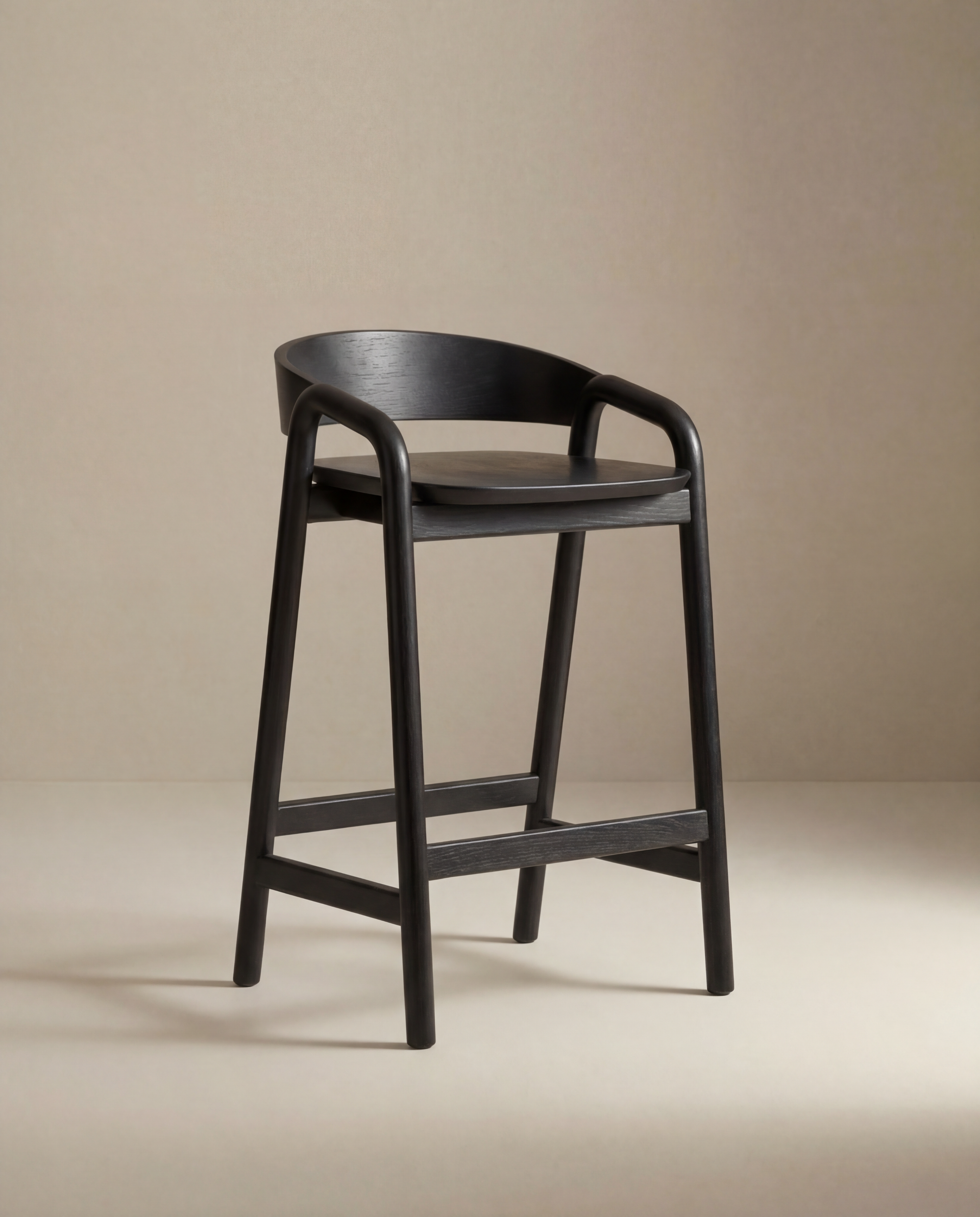 The Inlay Counter Stool | Wood Seat by Wooden Stories is a modern Danish counter stool in black wood with a curved backrest and footrest, ideal for stylish kitchen island seating, shown against a plain beige background.