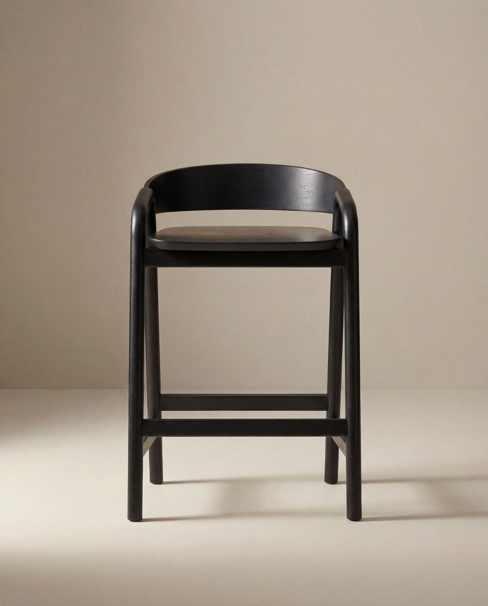 The Wooden Stories Inlay Counter Stool | Wood Seat is a modern black solid oak bar stool with a curved backrest and round seat, shown against a plain beige background.
