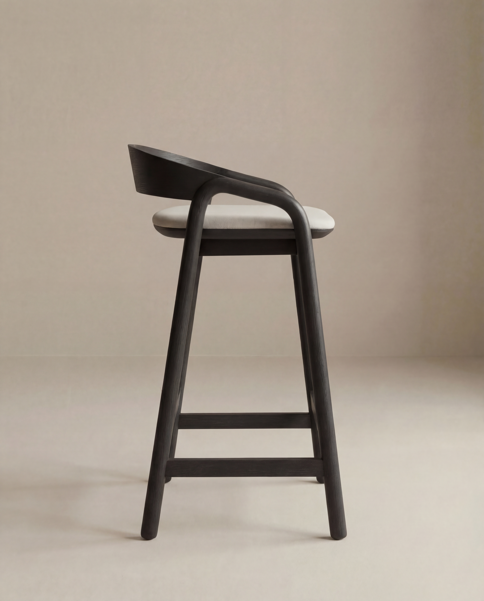 The Inlay Counter Stool | Fabric Seat by Wooden Stories features a solid oak frame, curved backrest, and light fabric seat, shown in profile against a beige background.