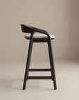 The Inlay Counter Stool | Fabric Seat by Wooden Stories features a solid oak frame, curved backrest, and light fabric seat, shown in profile against a beige background.