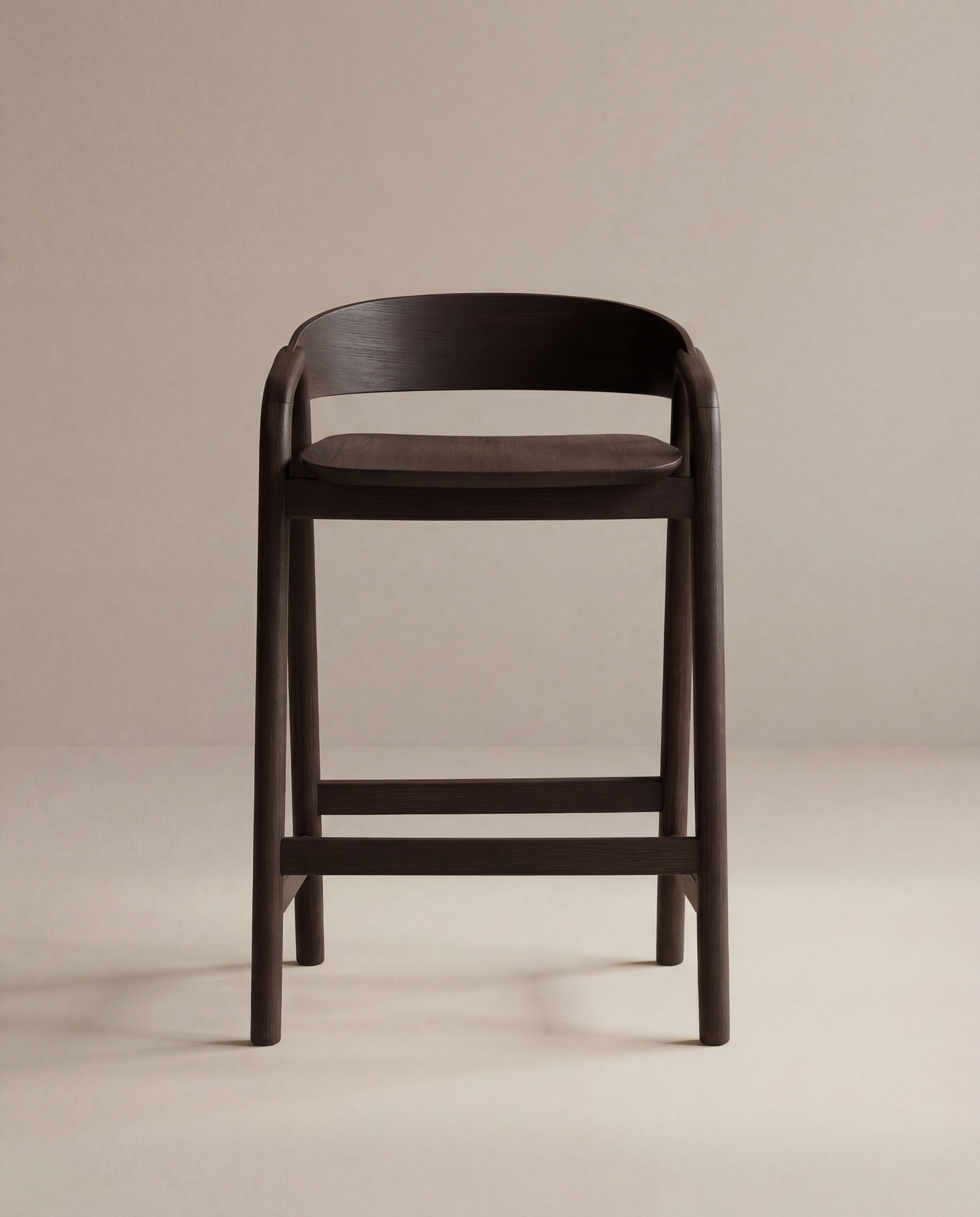 The Inlay Counter Stool | Wood Seat by Wooden Stories features modern Danish design in dark wood with a curved backrest and footrest, ideal for stylish kitchen island seating, shown here on a plain beige background.