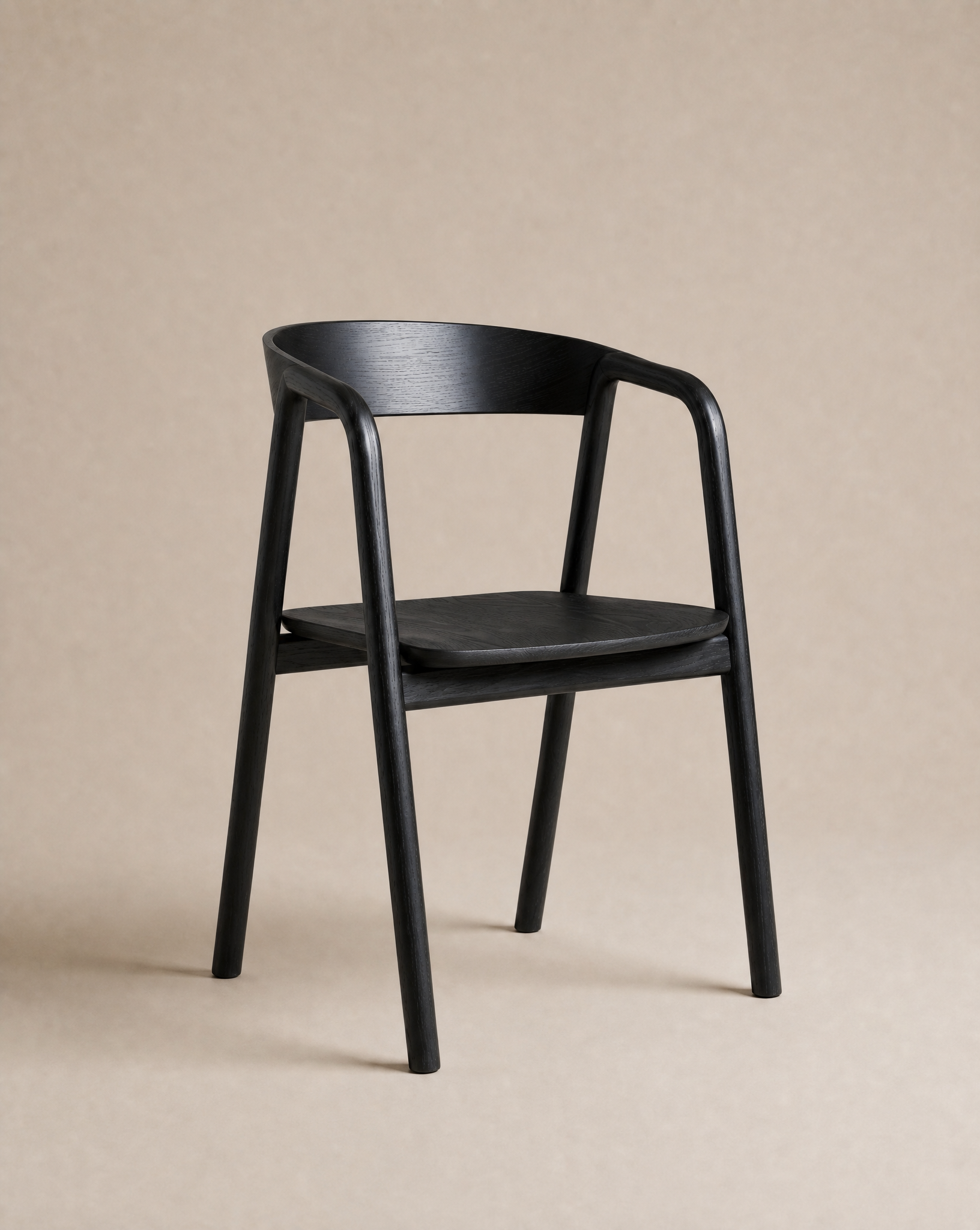 A sleek black "Inlay Dining Chair | Wood" by Wooden Stories, featuring a curved backrest and armrests inspired by the Danish Collection, is showcased against a plain beige background.