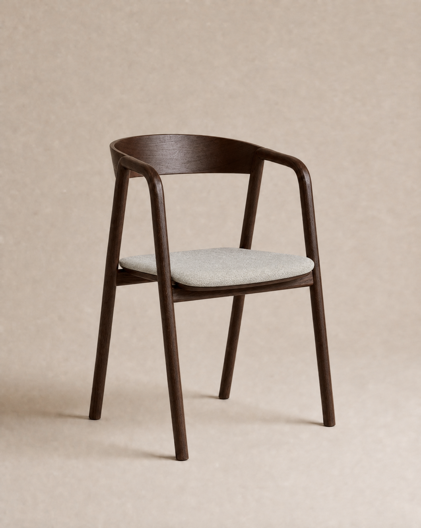 The Inlay Dining Chair | Fabric from Wooden Stories features a contemporary solid oak frame with a curved backrest and armrests, complemented by a light beige upholstered seat cushion. Inspired by the Danish Collection, this modern chair is set against a simple, solid beige background.
