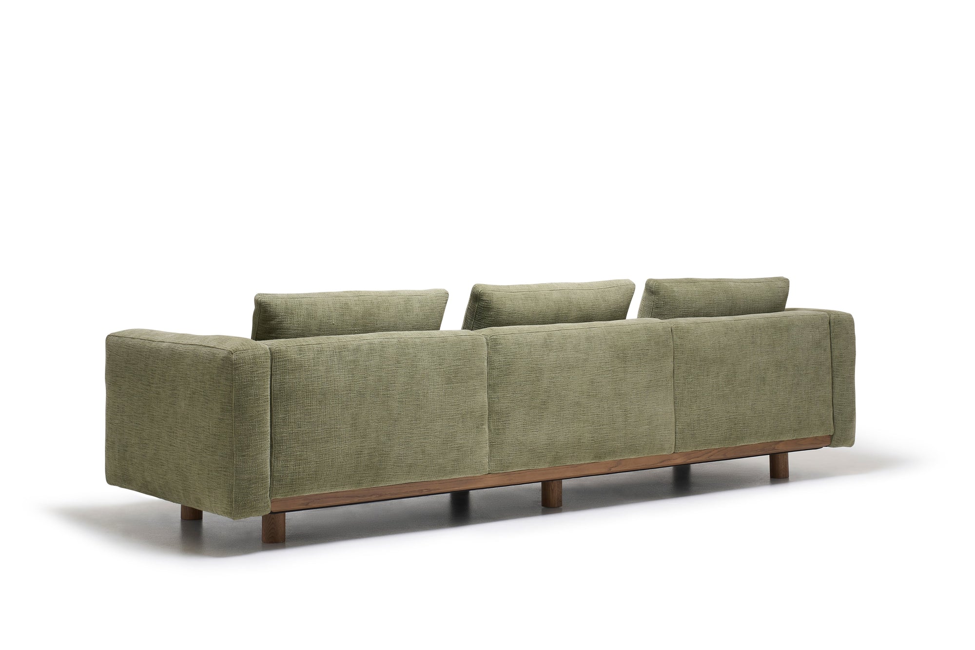 The Islet Sofa | Fabric by Wooden Stories is a green, modern piece featuring three back cushions and wooden legs, shown from the back against a white background.
