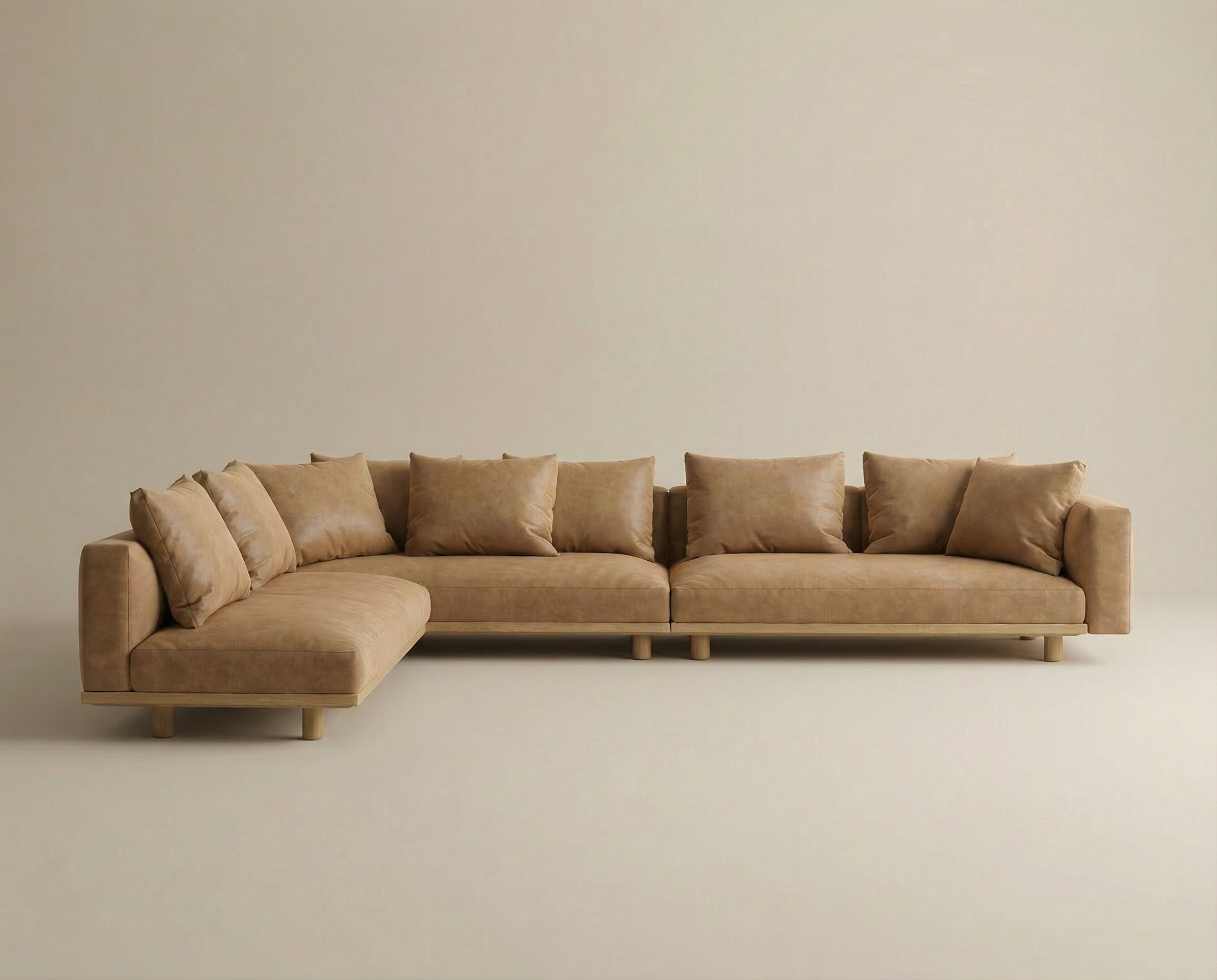 The Islet Modular Sofa | Leather • M2 by Wooden Stories is a large, modern L-shaped tan leather sectional with seven matching back cushions, clean lines, and low wooden legs, set against a plain beige background.