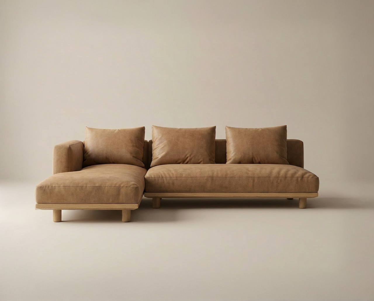 The Islet Modular Sofa | Leather • M3 by Wooden Stories, an L-shaped sectional with light brown upholstery and matching cushions, sits on a light beige floor against a neutral wall.