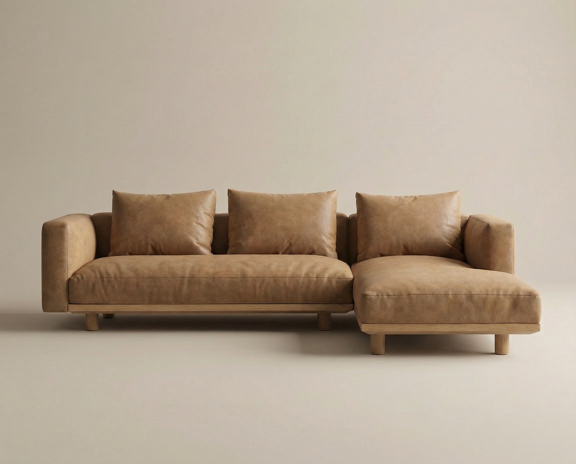 The Islet Modular Sofa | Leather • M1 by Wooden Stories is a modern tan leather sectional with wide armrests, three matching cushions, and a right-side chaise, shown against a plain beige background.