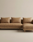 The Islet Modular Sofa | Leather • M1 by Wooden Stories is a modern tan leather sectional with wide armrests, three matching cushions, and a right-side chaise, shown against a plain beige background.