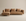 The Islet Modular Sofa | Leather • M1 by Wooden Stories is a modern light brown leather sectional with three seat cushions, three back pillows, and a left-side chaise, shown against a beige background.