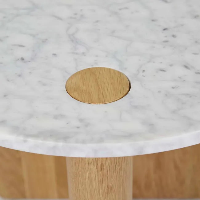 A close-up of the Wooden Stories Pivot Side Table | Light Oak shows its white marble top with a circular wooden inlay and partially visible solid wood legs, reflecting Danish-inspired design.