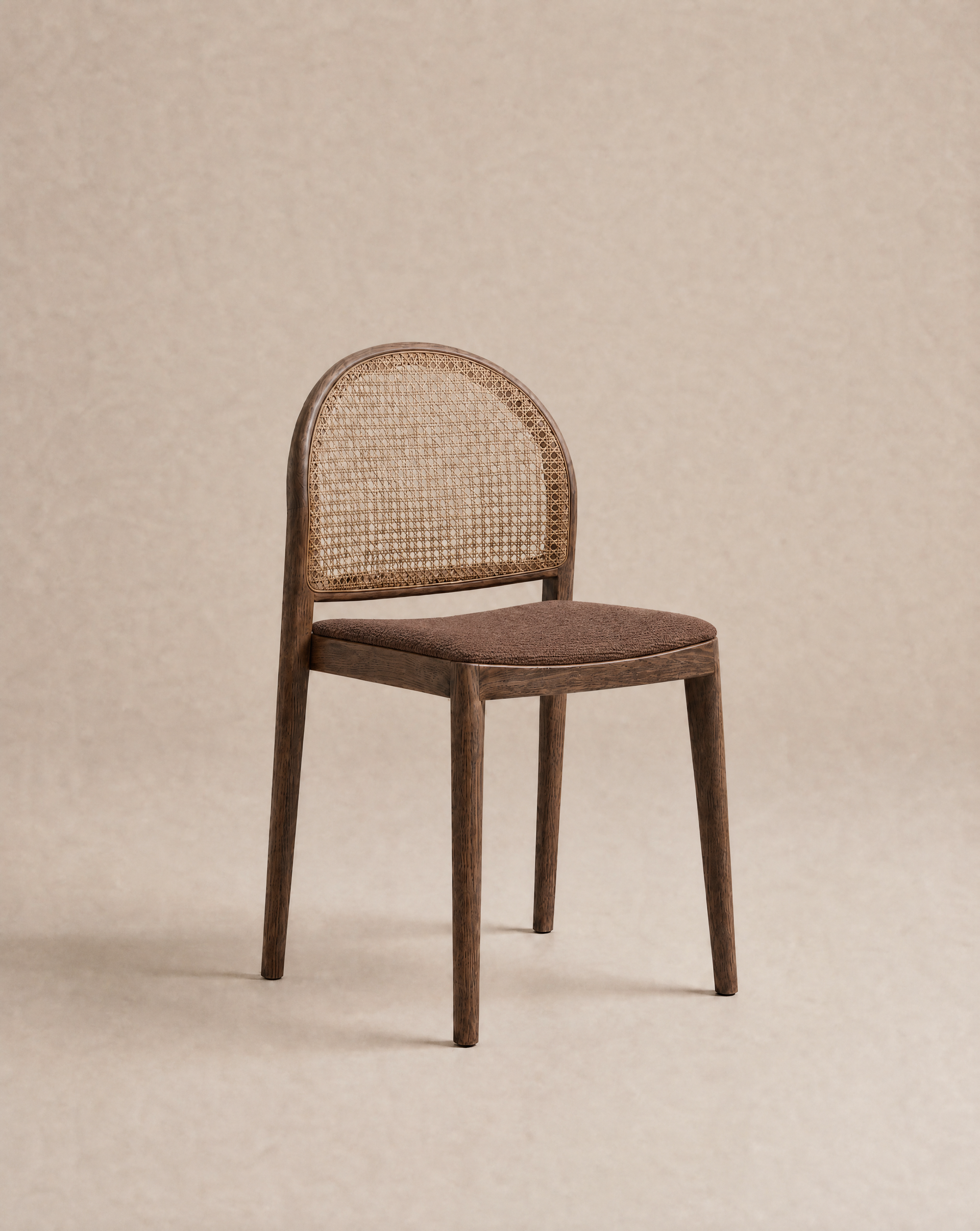 The Wooden Stories Luk Dining Chair | Fabric Seat features a cane weave rattan backrest and a brown cushioned seat, displayed against a plain beige background.