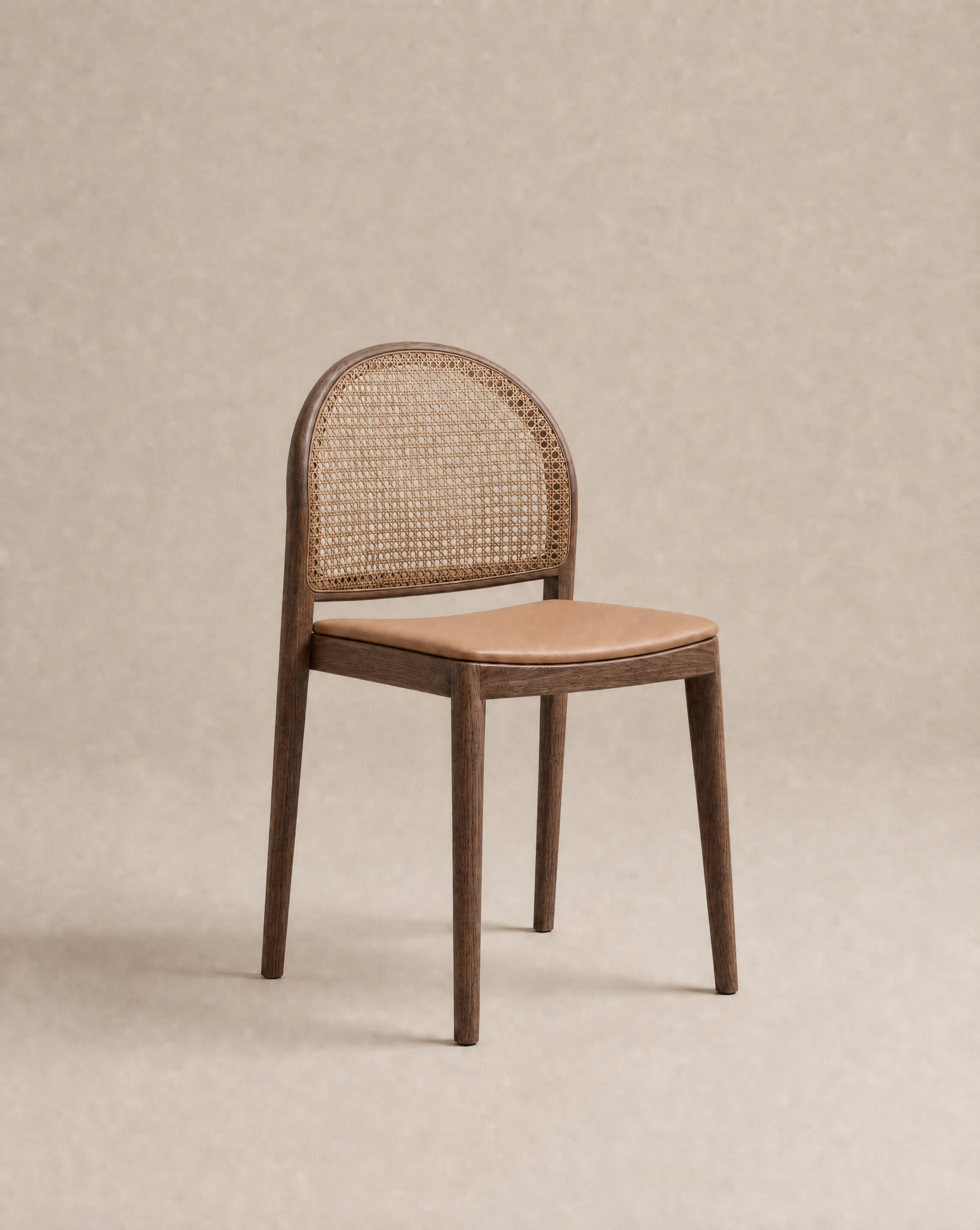 The Luk Dining Chair by Wooden Stories features a contract-grade wooden frame, rounded cane weave rattan backrest, and smooth light brown leather seat, shown against a plain beige background.