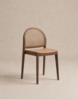 The Luk Dining Chair by Wooden Stories features a contract-grade wooden frame, rounded cane weave rattan backrest, and smooth light brown leather seat, shown against a plain beige background.