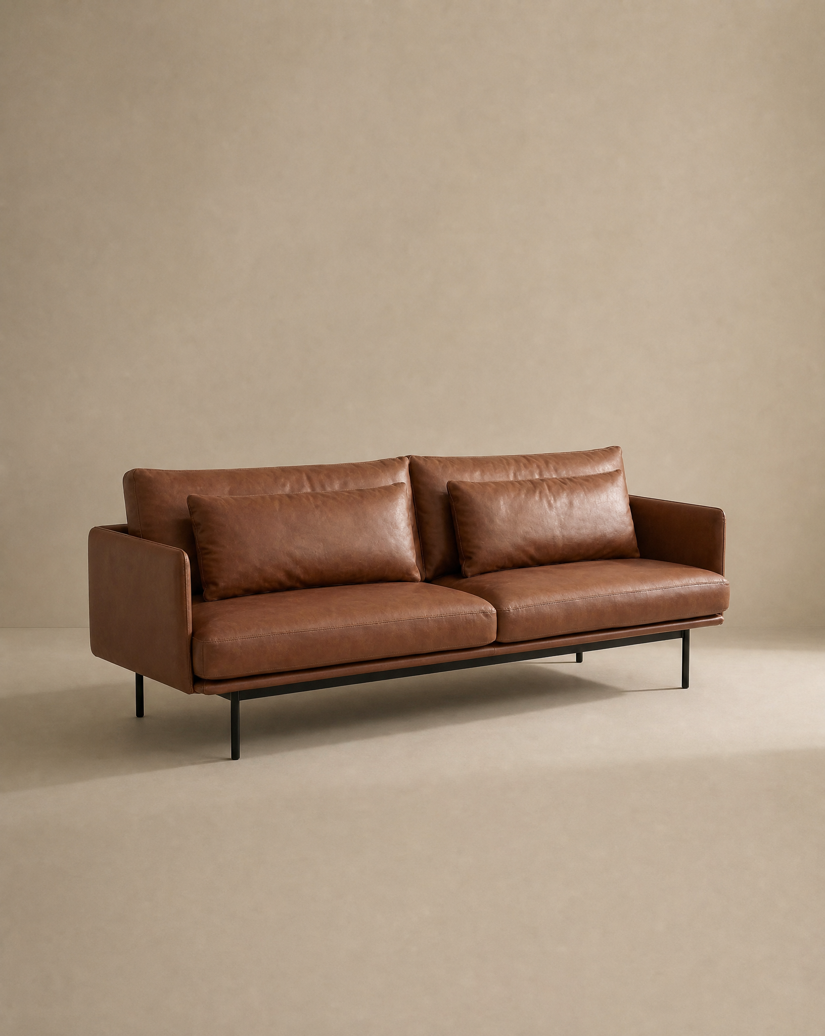 Introducing the Cherry Sofa | Leather by Wooden Stories—a modern brown leather 3-seater featuring two spacious seat and back cushions, sleek slim armrests, and sturdy black metal legs. Shown against a plain beige background, this sofa is perfect for bringing exceptional comfort and contemporary style to any modern living space.