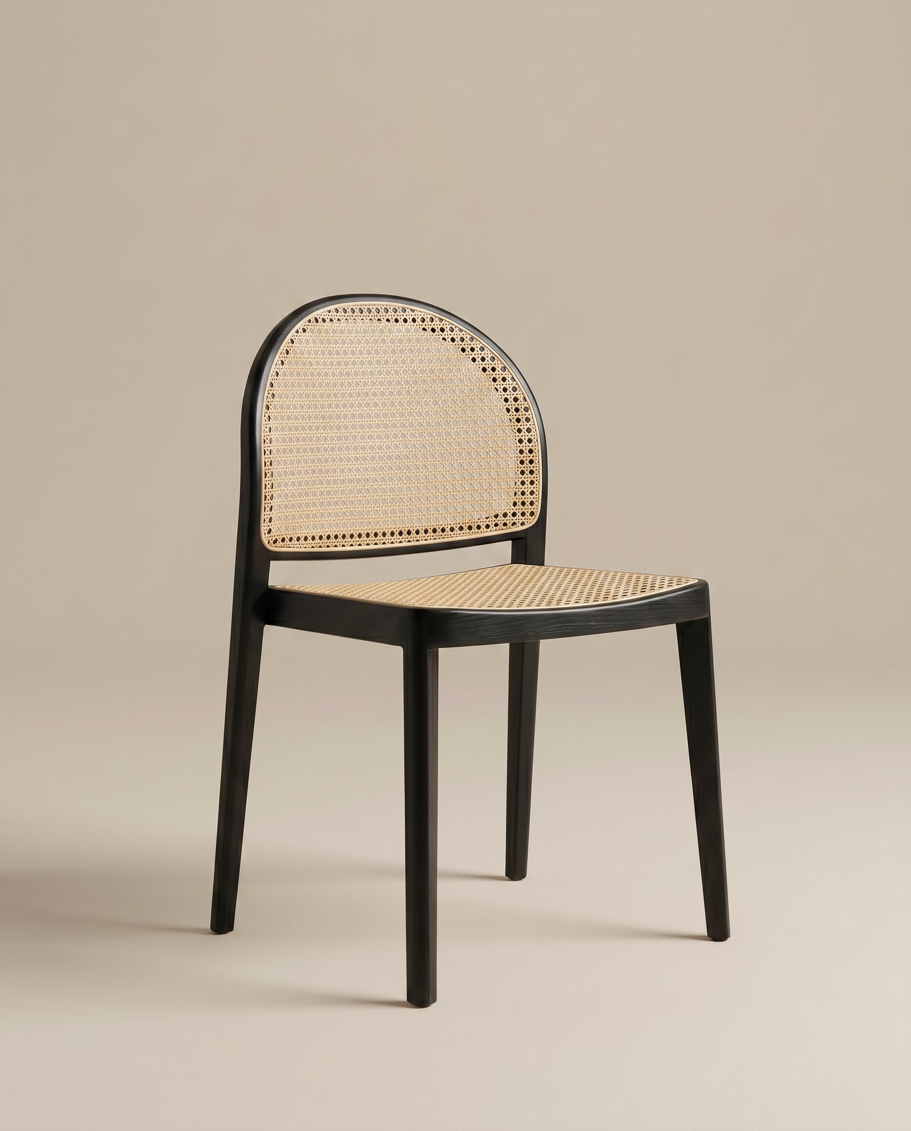 The Luk Dining Chair by Wooden Stories features a modern arch silhouette with a black wooden frame and cane weave rattan seat and backrest, showcased against a plain beige background.