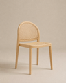 The Luk Dining Chair by Wooden Stories features a light wooden arch silhouette, rounded backrest, and woven cane seat. Set against a beige background, its minimalist design and rattan details add modern, contract-grade style.