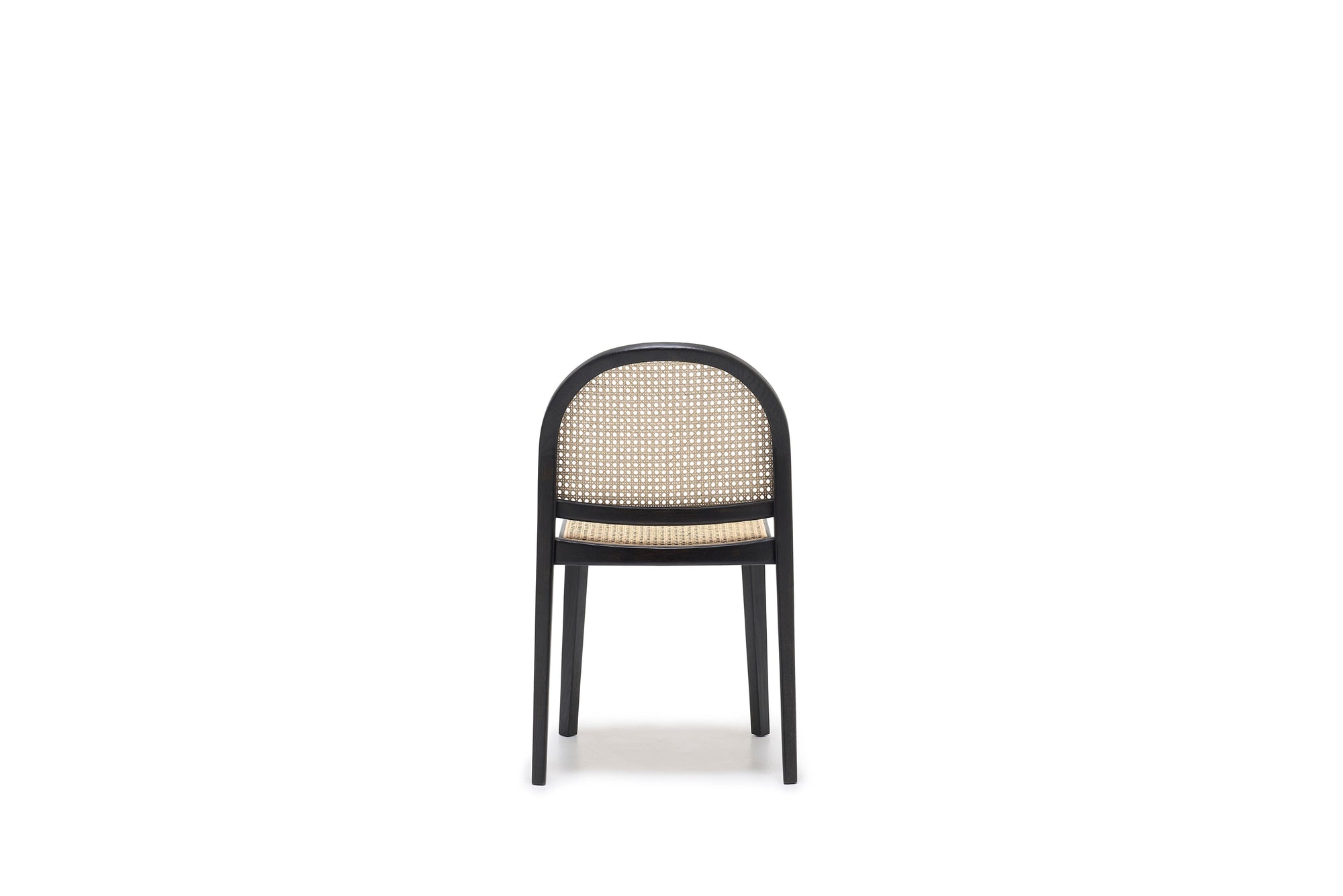 The Luk Dining Chair by Wooden Stories features a rounded backrest, black frame, and cane weave rattan seat and back. Shown on a plain white background, it boasts contract grade construction for lasting durability.