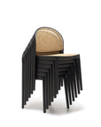 A stack of six contract-grade Wooden Stories Luk Dining Chairs with rounded backs and cane weave rattan seats, arranged neatly against a white background.