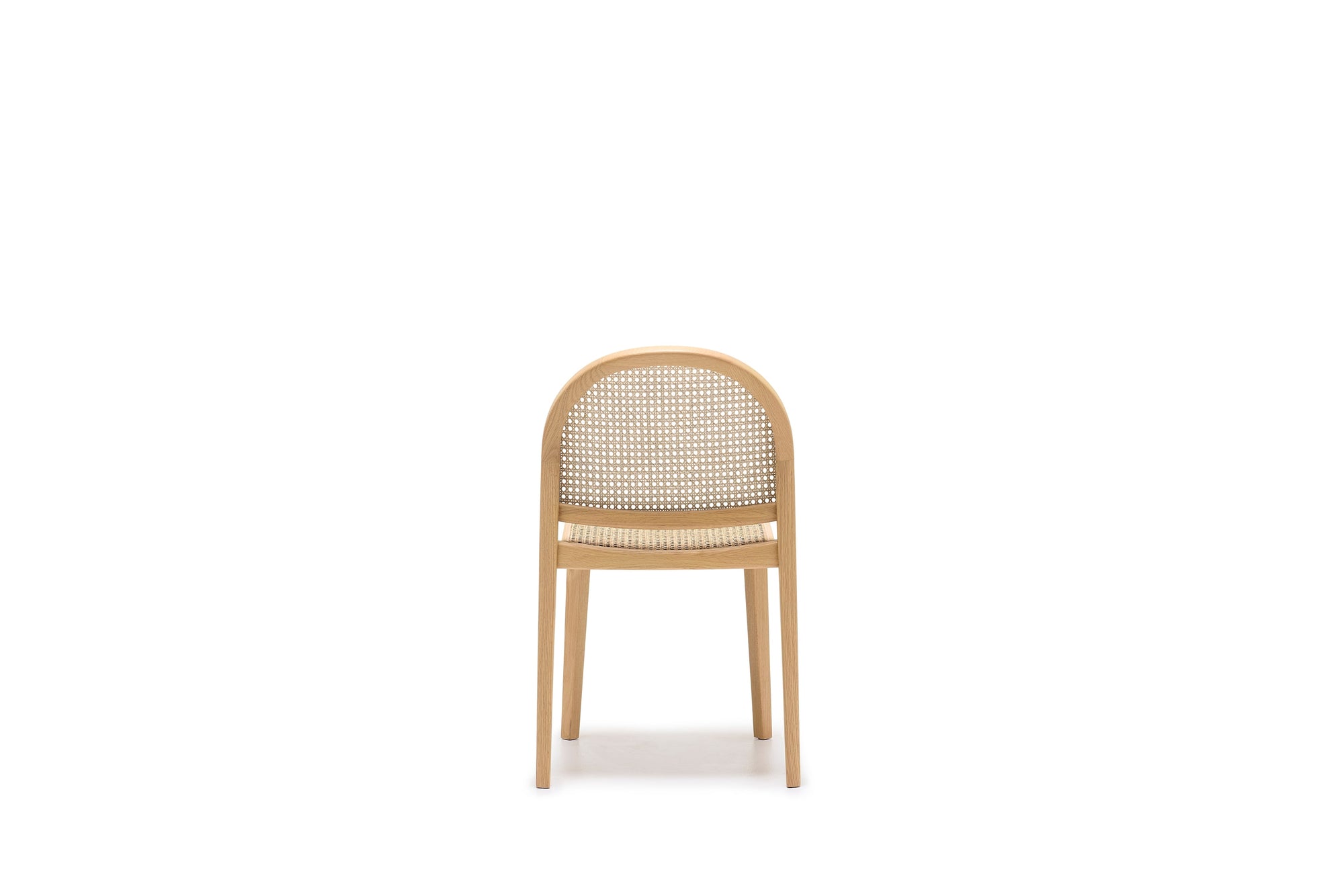 The Wooden Stories Luk Dining Chair features a simple, modern design with a rounded backrest and cane weave rattan seat, photographed front-facing on a white backdrop. This contract-grade chair combines style and durability for any space.