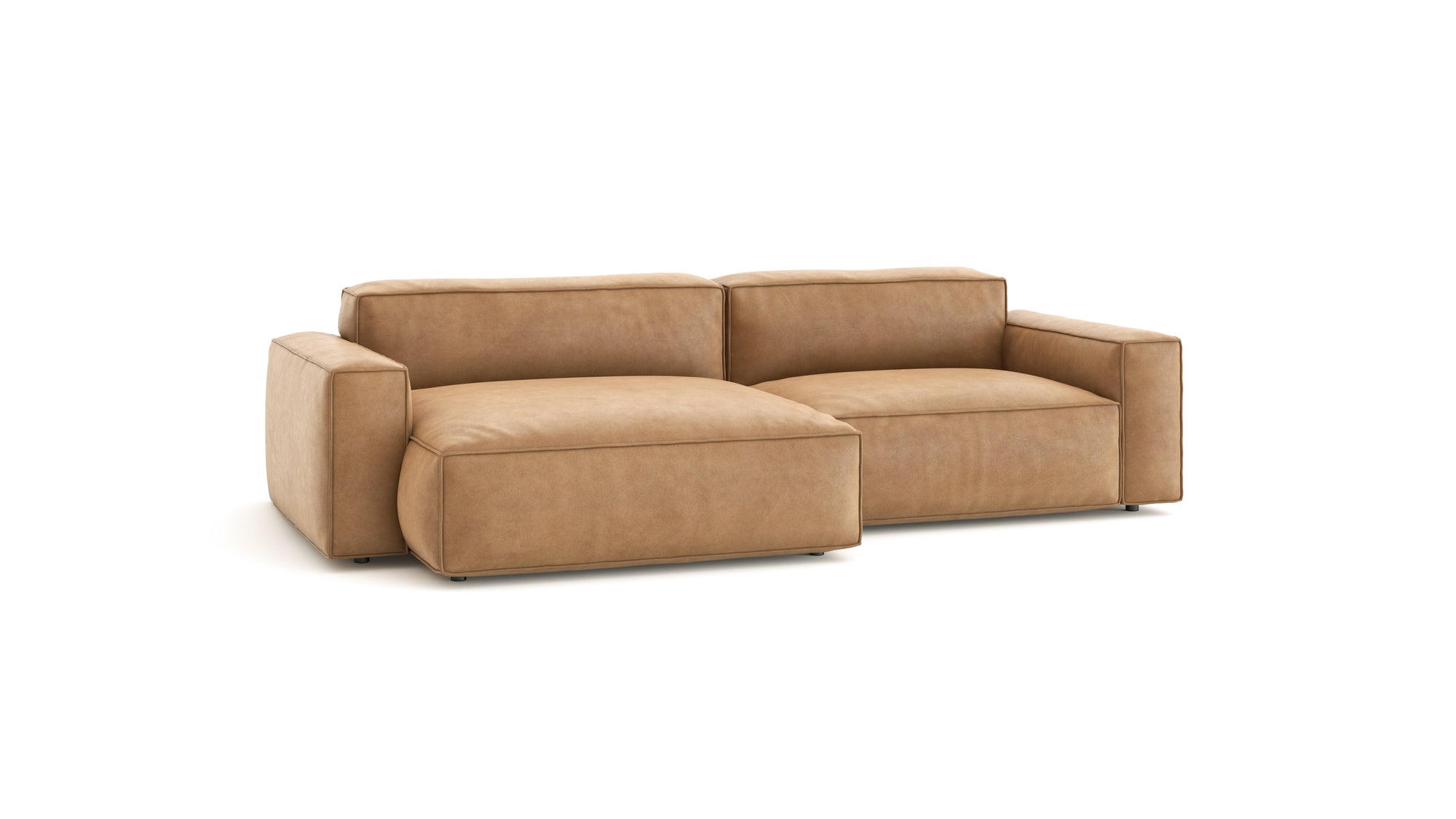 The Baker Modular Sofa | Leather • M5 by Wooden Stories is a modern tan leather sofa with wide armrests, plush cushions, and a left-side chaise lounge, shown against a plain white background.