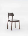 Three Wooden Stories Noki Dining Chairs in Espresso Oak are lined up against a plain white background. Each contract-grade solid wood chair features a unique color: black with gray fabric, dark brown with gray fabric, and light wood without upholstery.