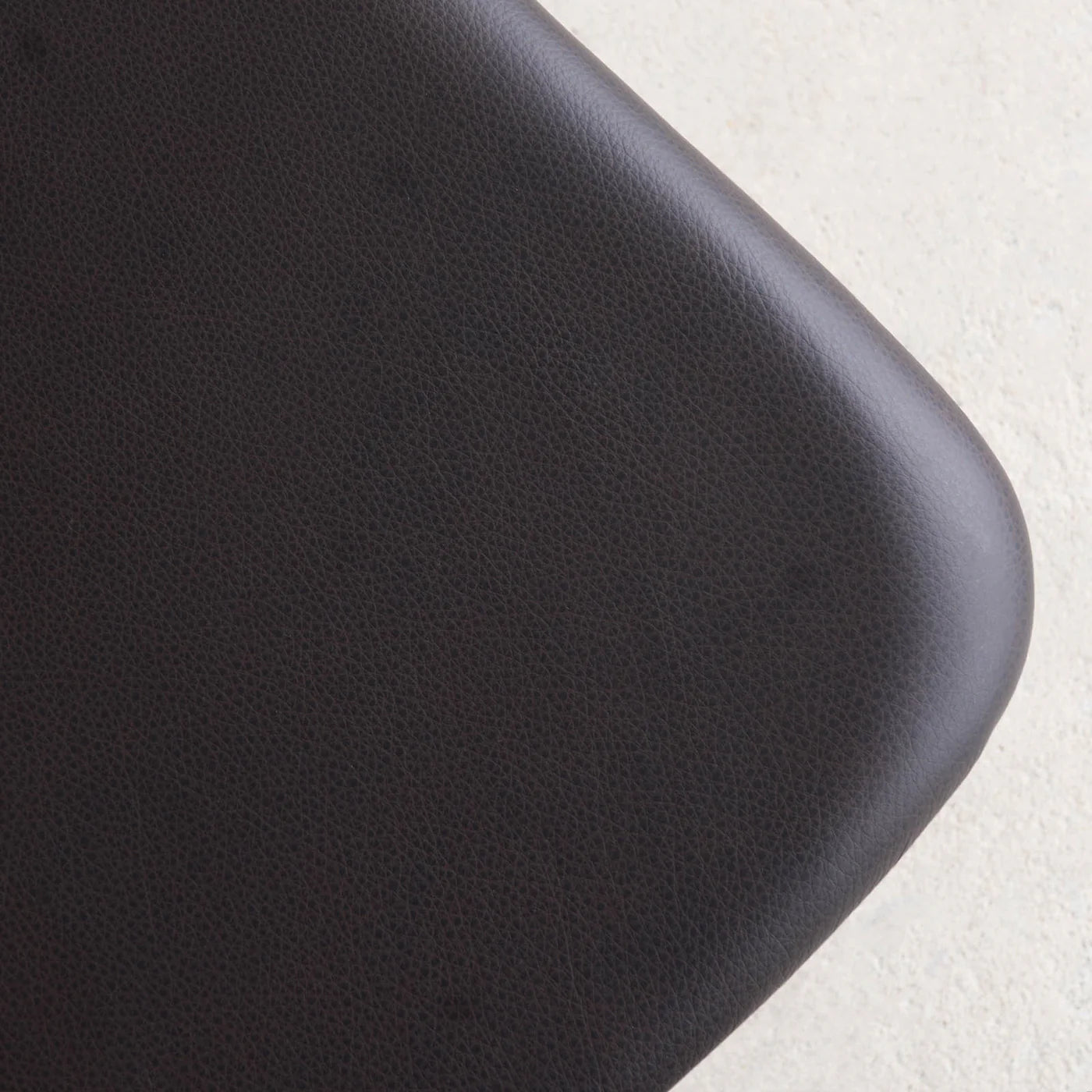 Close-up of the rounded, textured black leather seat cushion on the Noki Dining Chair by Wooden Stories, crafted in black oak—a detail reflecting its Japanese-inspired design.