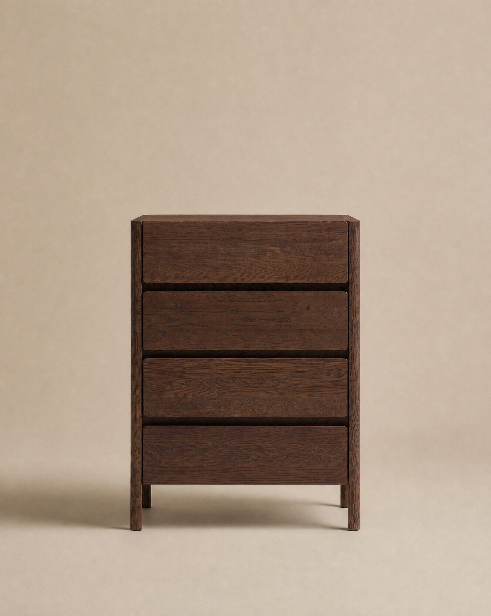 The Nell Tall Dresser by Wooden Stories stands against a plain beige background. Part of the elegant Danish Collection, this piece features a dark wood finish, three spacious drawers, and showcases simple, modern design with clean lines and a smooth surface. Perfect for bedroom storage, each drawer effortlessly glides open on premium metal runners.
