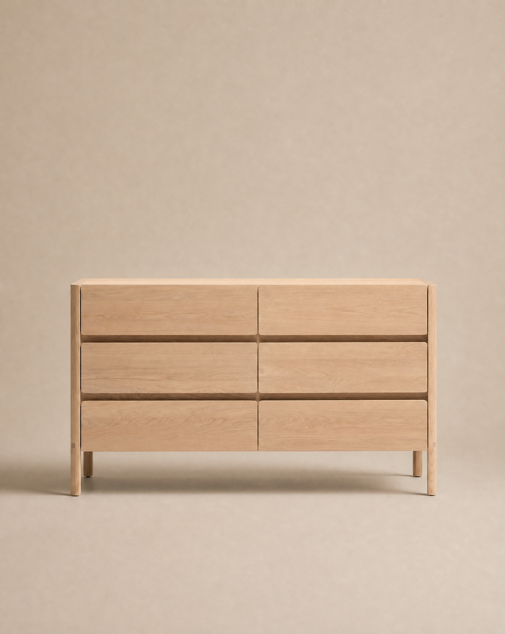 The Nell Tall Dresser by Wooden Stories, from the Danish Collection, stands against a neutral beige background. Featuring six drawers arranged in two columns, this light wood dresser offers a simple and modern design with clean lines, premium metal runners for effortless use, and a handleless silhouette—making it an ideal option for stylish bedroom storage.
