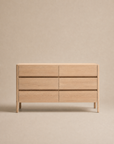 The Nell Tall Dresser by Wooden Stories, from the Danish Collection, stands against a neutral beige background. Featuring six drawers arranged in two columns, this light wood dresser offers a simple and modern design with clean lines, premium metal runners for effortless use, and a handleless silhouette—making it an ideal option for stylish bedroom storage.