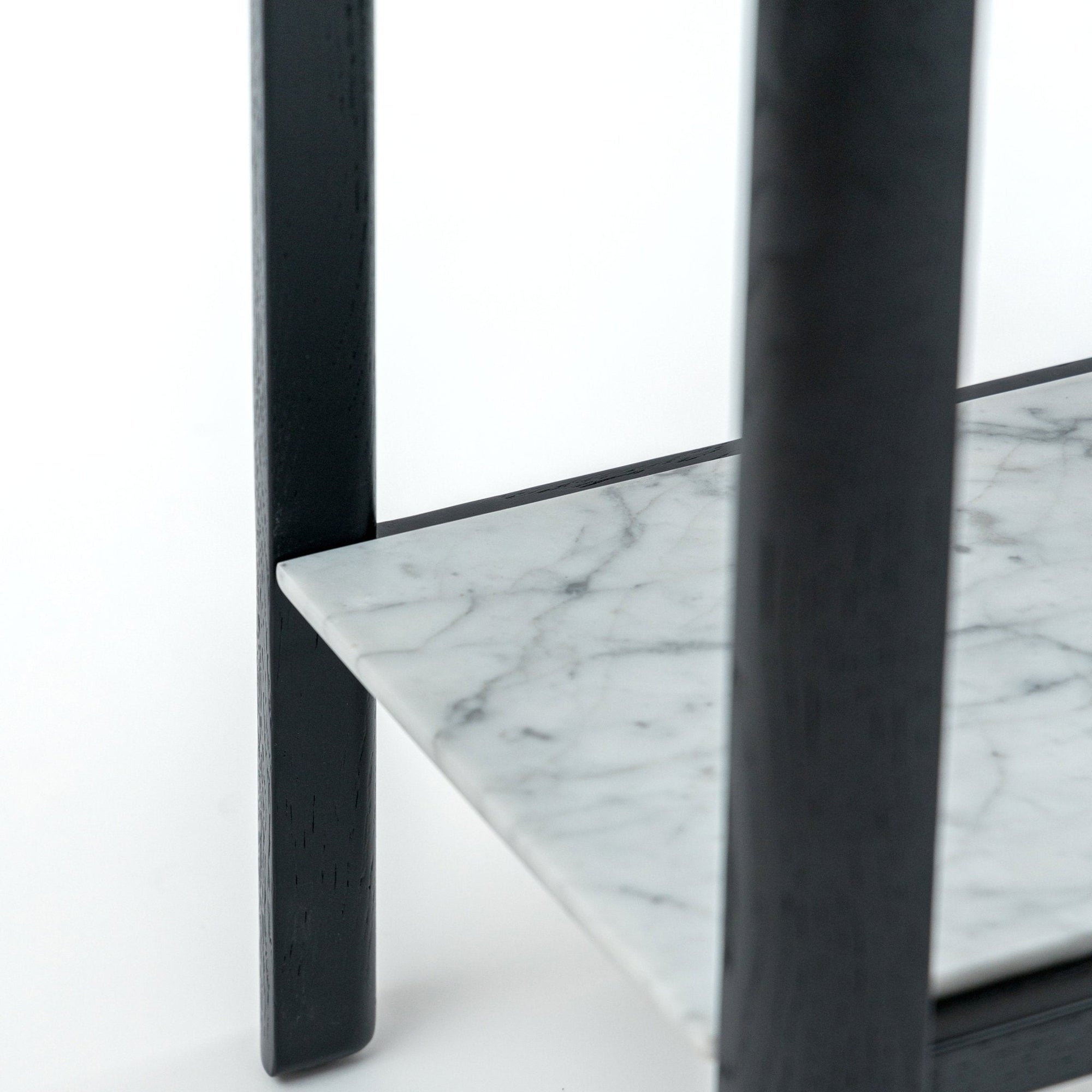 Close-up of the Nell Console by Wooden Stories, featuring a white marble shelf with grey veining and black oak legs—a refined take on Scandinavian design.