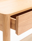 A close-up of the Wooden Stories Nell Console in Light Oak with Stone shows its solid oak grain, clean lines, and minimalist Scandinavian design, with a partially open drawer against a white background.