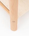 Close-up of the Nell Console by Wooden Stories, featuring a solid light oak leg with visible joint detail next to a beige stone tabletop, set against a white background.