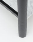 Close-up of the Nell Console by Wooden Stories: black oak edge, gray cylindrical leg, and polished white marble top with subtle veining—Scandinavian-inspired elegance set against a smooth white background.