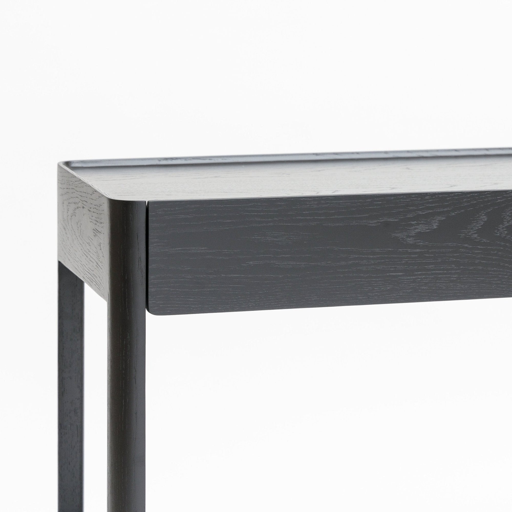 A close-up of the Nell Console by Wooden Stories in black oak with stone, featuring a minimalist rectangular top and straight legs, photographed against a plain white background to highlight its refined Scandinavian design.