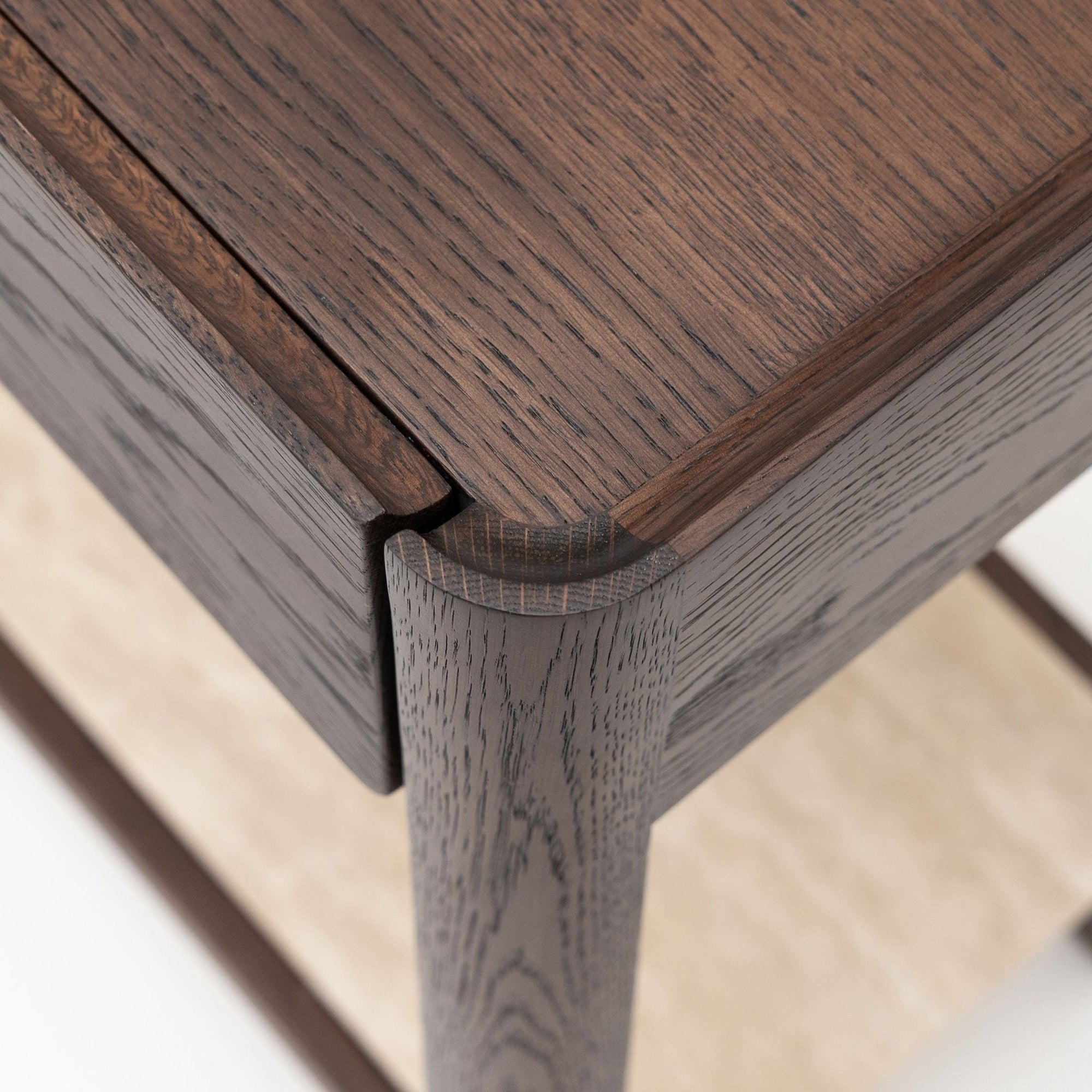 Close-up of the Wooden Stories Nell Console in Espresso Oak with Stone, highlighting the joinery where the leg meets the tabletop and a lighter stone lower shelf, with visible wood grain evoking Scandinavian design.