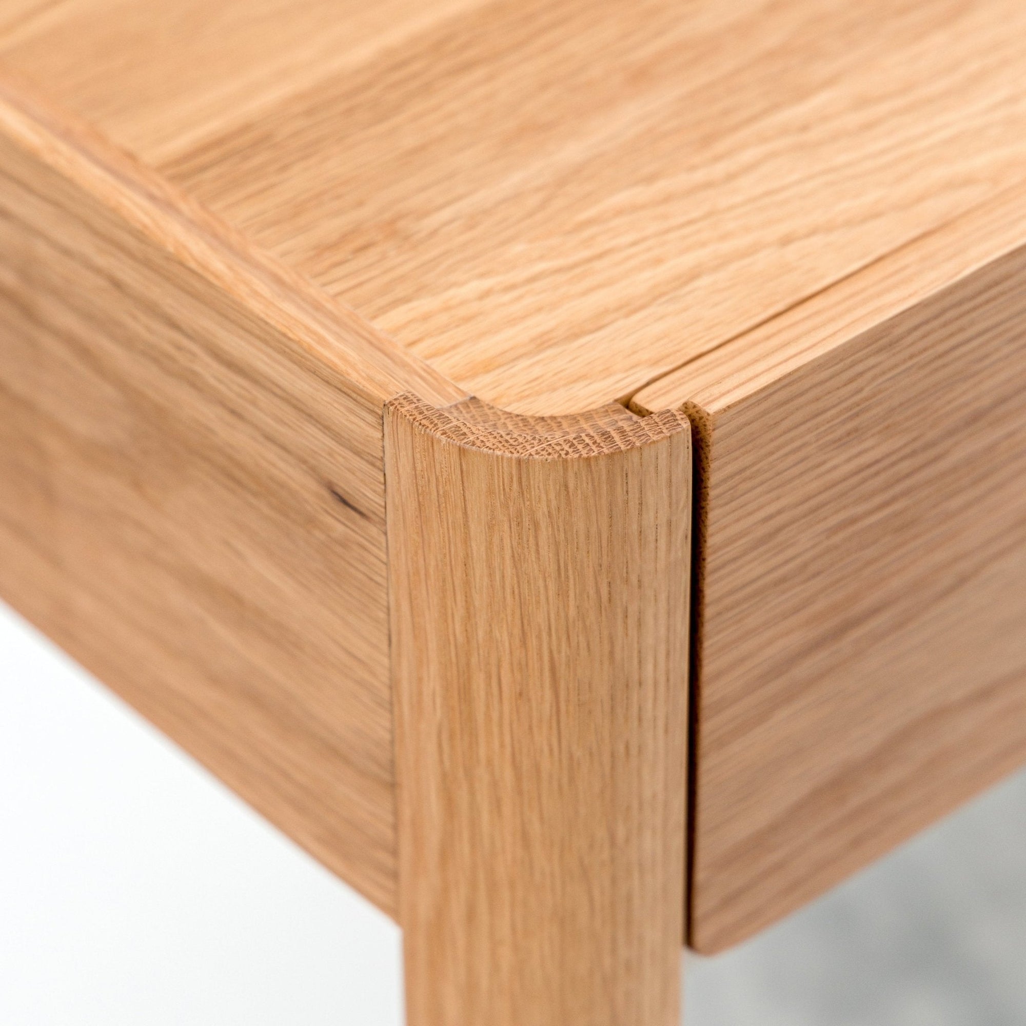 A close-up of the Nell Console by Wooden Stories in light oak with stone, highlighting smooth, rounded edges and natural wood grain. The refined Scandinavian design is shown through its craftsmanship and elegant joinery details.