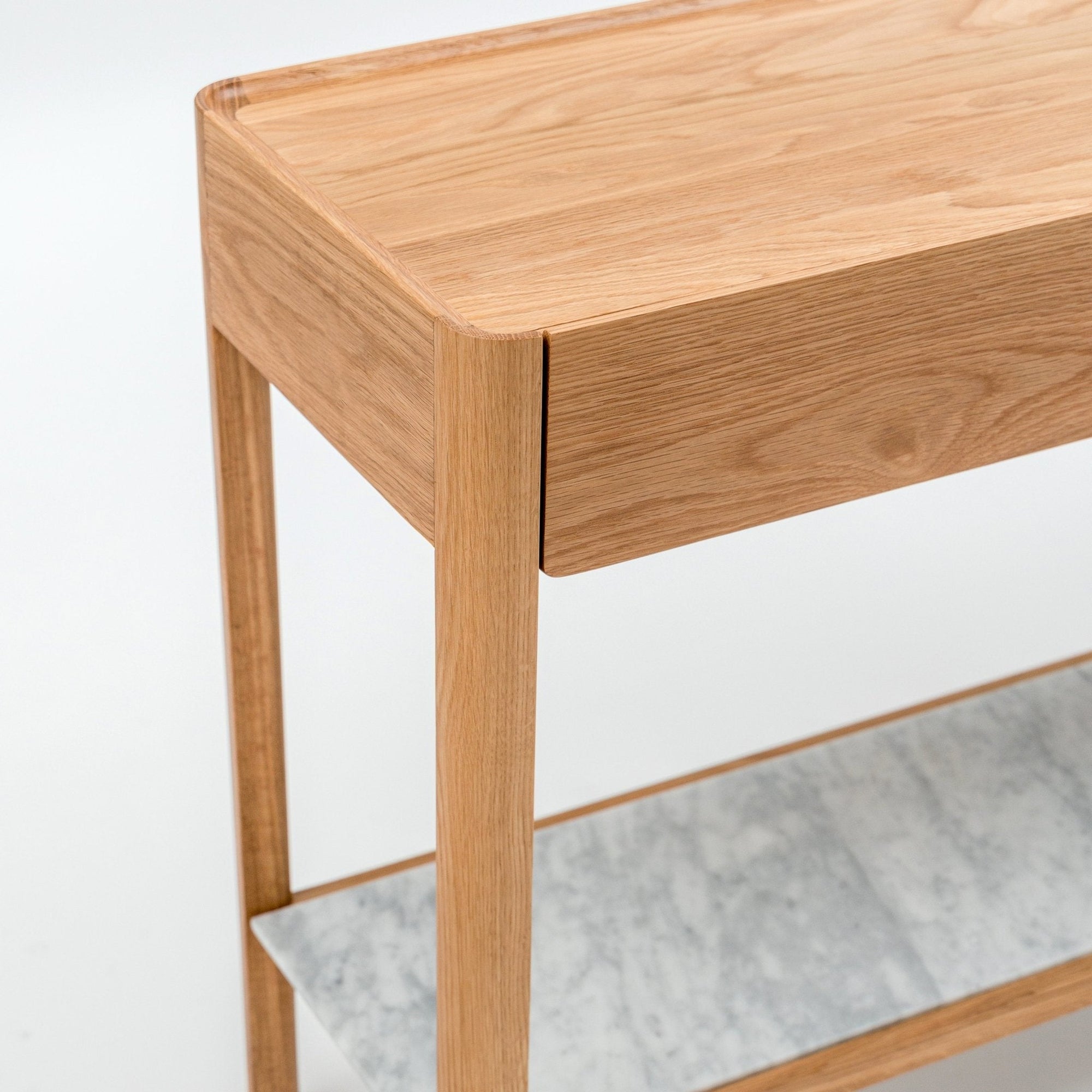 The Nell Console by Wooden Stories features a minimalist design in light oak with a gray stone lower shelf, inspired by Scandinavian style. Crafted from solid oak, it's set against a plain white background.