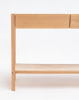 The image shows the right side of the Wooden Stories Nell Console in Light Oak with Stone—a minimalist Scandinavian table with clean lines, a lower shelf, and two drawers—set against a plain white background.