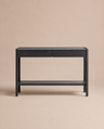 The Nell Console in Black Oak by Wooden Stories, from the Danish collection, is a minimalist piece featuring two drawers, a lower shelf, and rounded legs, styled against a solid neutral beige background.