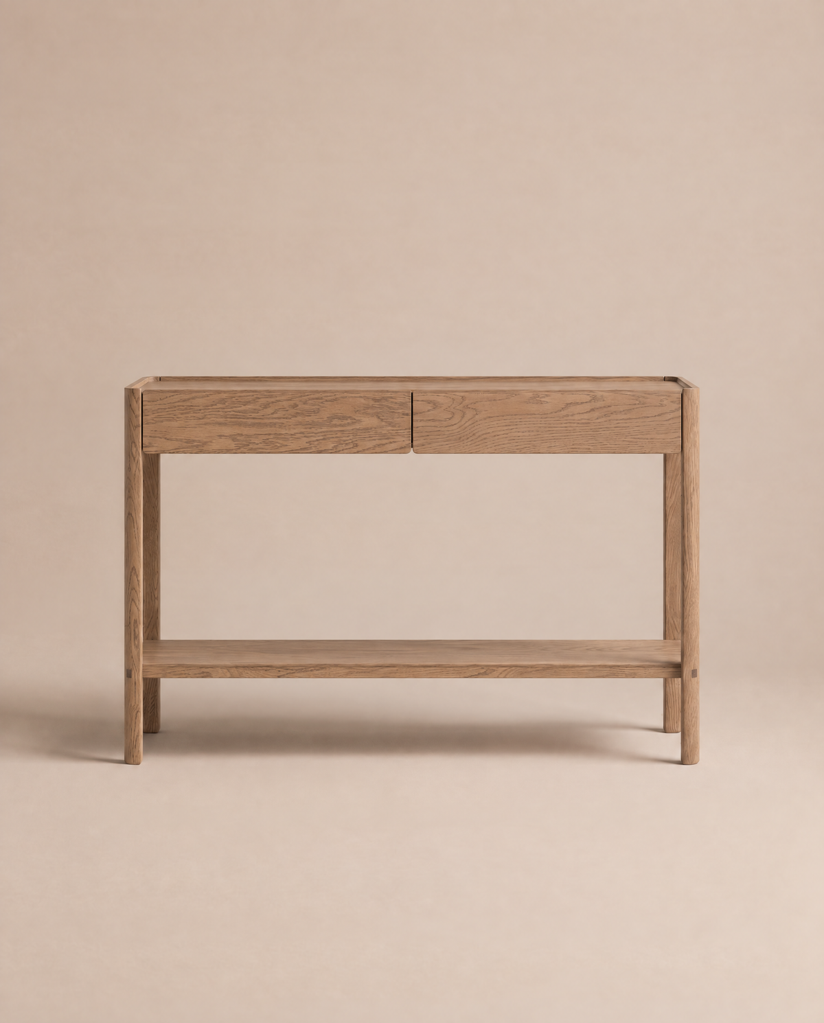The Nell Console | Latte Oak by Wooden Stories, crafted from solid oak, features two drawers and a lower shelf. Set against a plain beige background, its simple, modern silhouette highlights the natural wood grain in classic Scandinavian design.