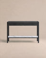 A minimalist black console table from Wooden Stories’ Danish collection, the Nell Console in Black Oak with Stone features two drawers and a white stone lower shelf. Set against a plain beige background, this piece embodies Scandinavian design principles with its refined simplicity and timeless appeal.