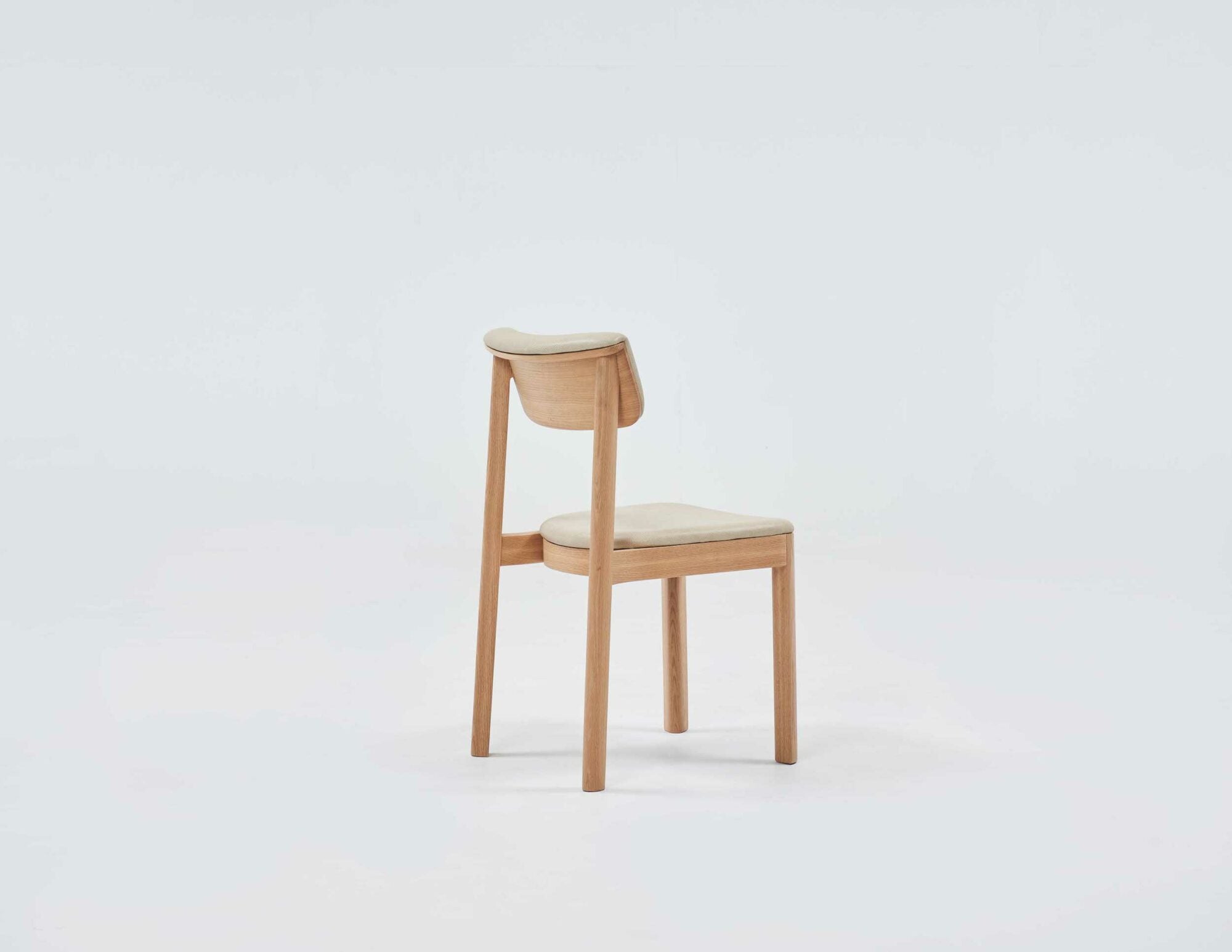 The Noki Dining Chair - Light Oak - Leather by Wooden Stories, designed by Ryota Yokozeki, features a simple wooden frame with light leather padding and showcases elegant Japanese design against a plain, light backdrop.