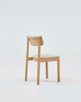 The Noki Dining Chair - Light Oak - Leather by Wooden Stories, designed by Ryota Yokozeki, features a simple wooden frame with light leather padding and showcases elegant Japanese design against a plain, light backdrop.