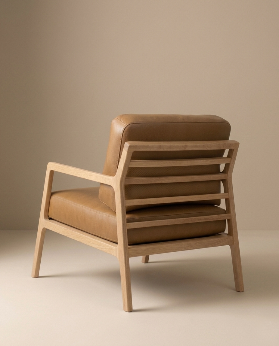 The Nysse Lounge Chair | Leather by Wooden Stories features clean, modern Scandinavian lines, a light wooden frame, and tan leather cushions. It’s shown angled against a beige background for a minimalist look.
